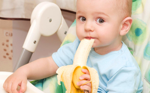Маленький мальчик ест банан 